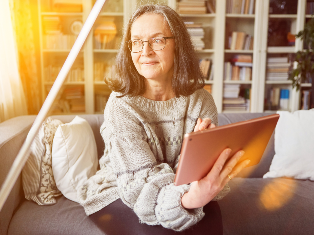 An elderly woman looking to the left while holding her tablet.